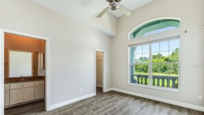A spacious room with a large window, a ceiling fan, and a view of greenery outside. - Port Boujee: Spacious 5-bedroom house in Port Charlotte with Pool, AC, WiFi (Port Charlotte)