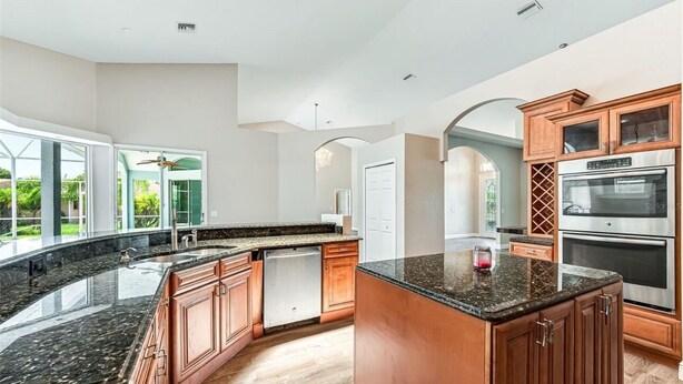 A modern kitchen with granite countertops, stainless steel appliances, and wooden cabinetry. - Port Boujee: Spacious 5-bedroom house in Port Charlotte with Pool, AC, WiFi (Port Charlotte)