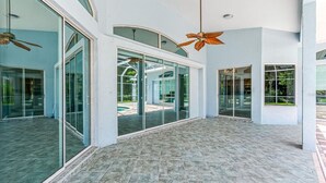 A spacious indoor area with large glass doors leading to an outdoor patio, ceiling fans, and a tiled floor. - Port Boujee: Spacious 5-bedroom house in Port Charlotte with Pool, AC, WiFi (Port Charlotte)
