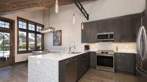A modern kitchen with dark wood cabinets, stainless steel appliances, and a marble island. - Amazing Views - Close to it All! (Big Sky)