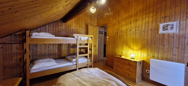 A wooden cabin room with bunk beds, a dresser, and a radiator.