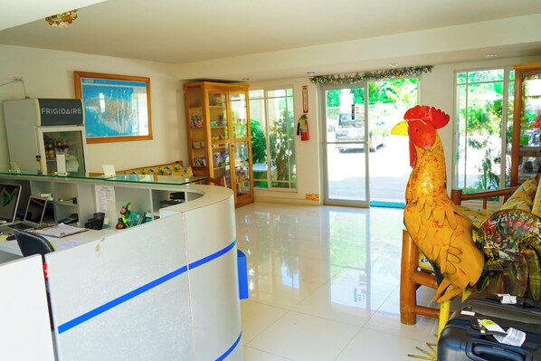 Un'area reception con un bancone in vetro, una grande mappa incorniciata appesa al muro, un mobiletto in legno e una grande decorazione a forma di gallo.