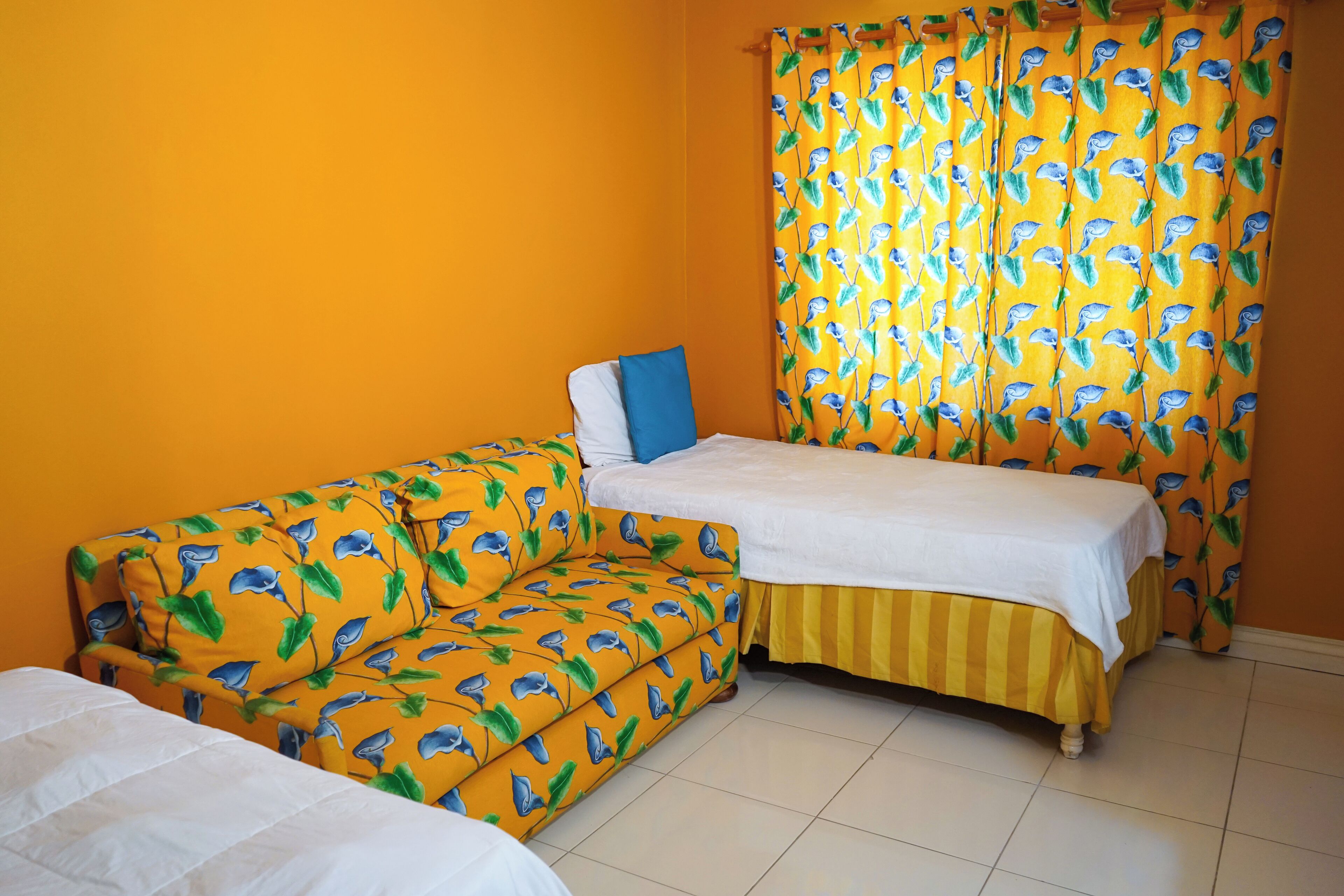 Una habitación con cama, sofá y cortina estampada con pájaros.