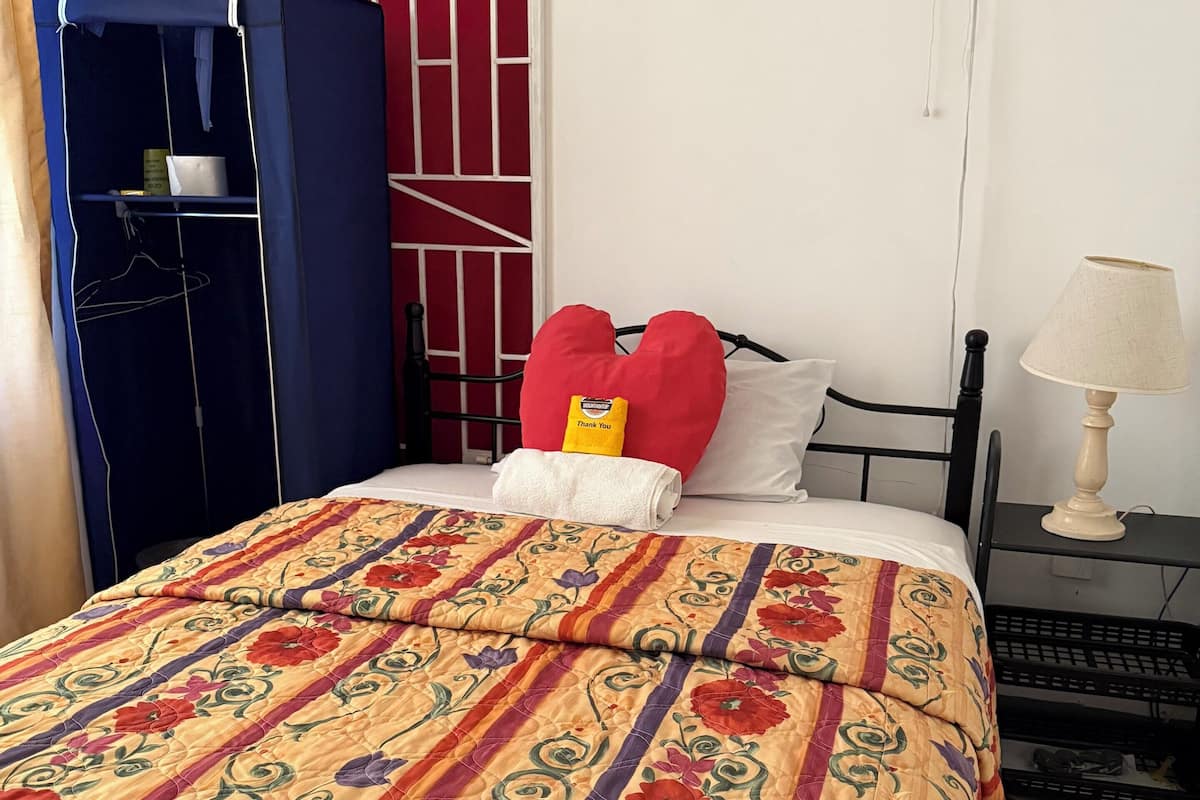 Un dormitorio con cama, mesita de noche, lámpara, armario y una puerta con cerradura.