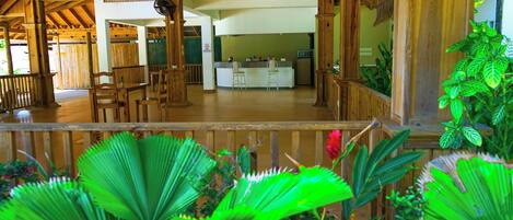 A wooden interior with a bar area, seating, and a view of the outside.