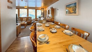 A dining area with a wooden table set for a meal, surrounded by wooden chairs.