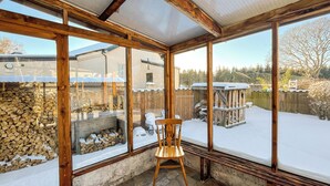 A sunroom with large windows, stone flooring, and a wooden chair.