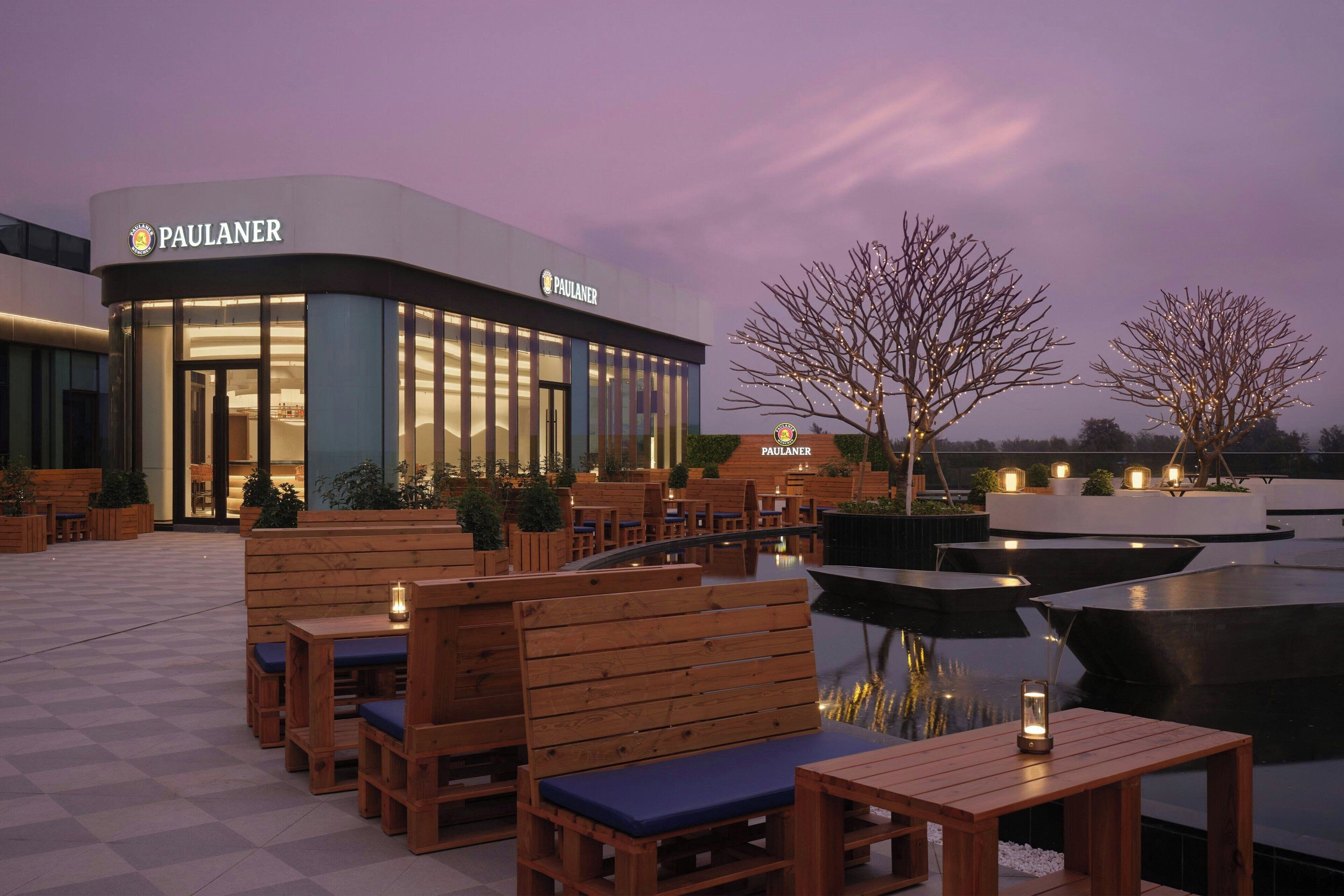 Un establecimiento Paulaner con terraza y una fuente de agua.