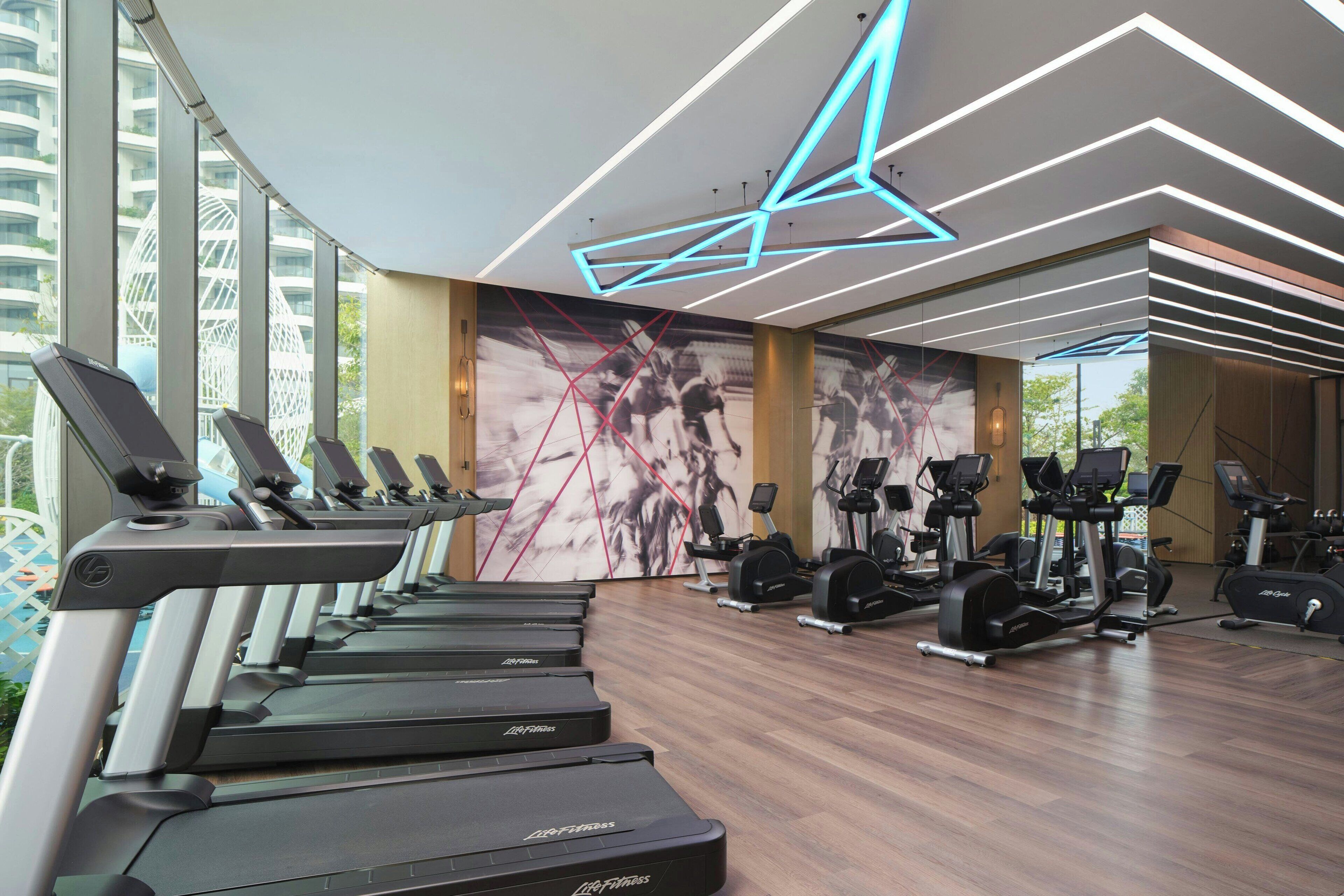 A modern gym with treadmills, elliptical machines, and weight equipment.