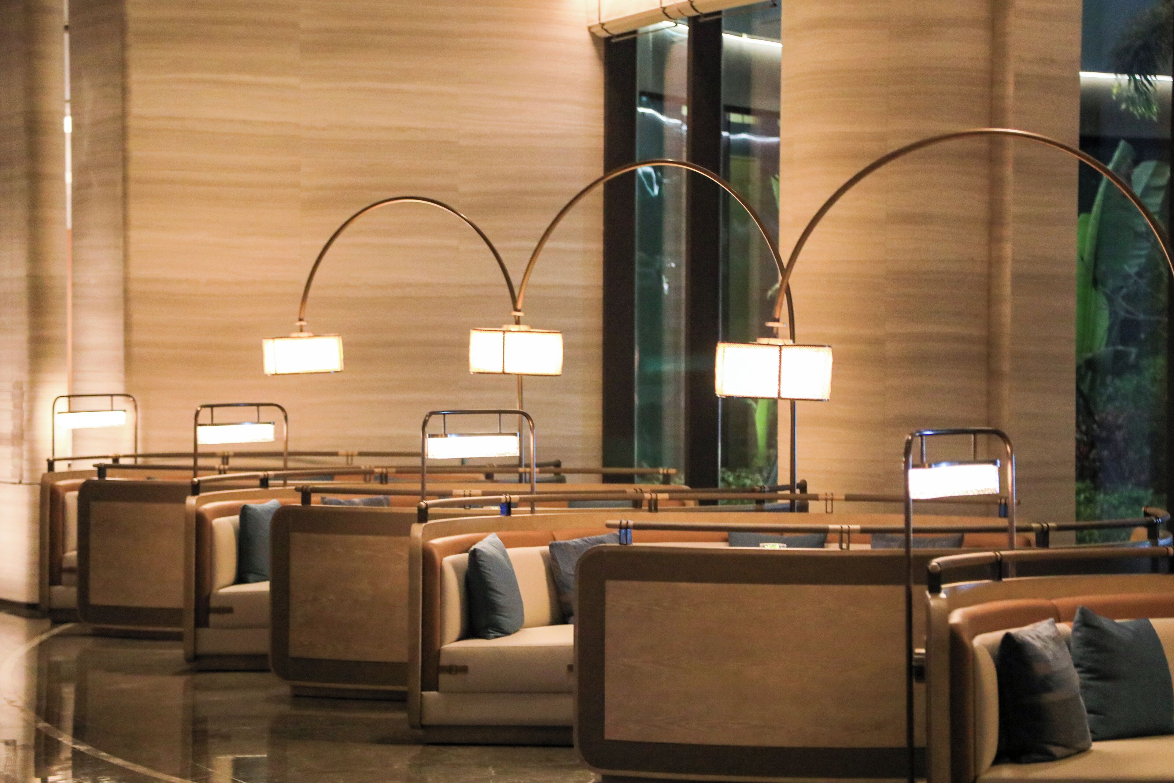 Um saguão de hotel com fileiras de assentos, um grande aquário e luminárias modernas.