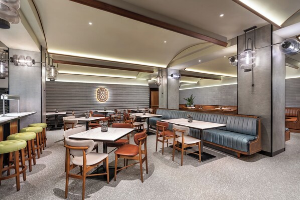 A modern restaurant interior with wooden tables and chairs, a blue booth seating area, and pendant lighting. - Four Points By Sheraton Bangkok, Sukhumvit 22 (Bangkok)