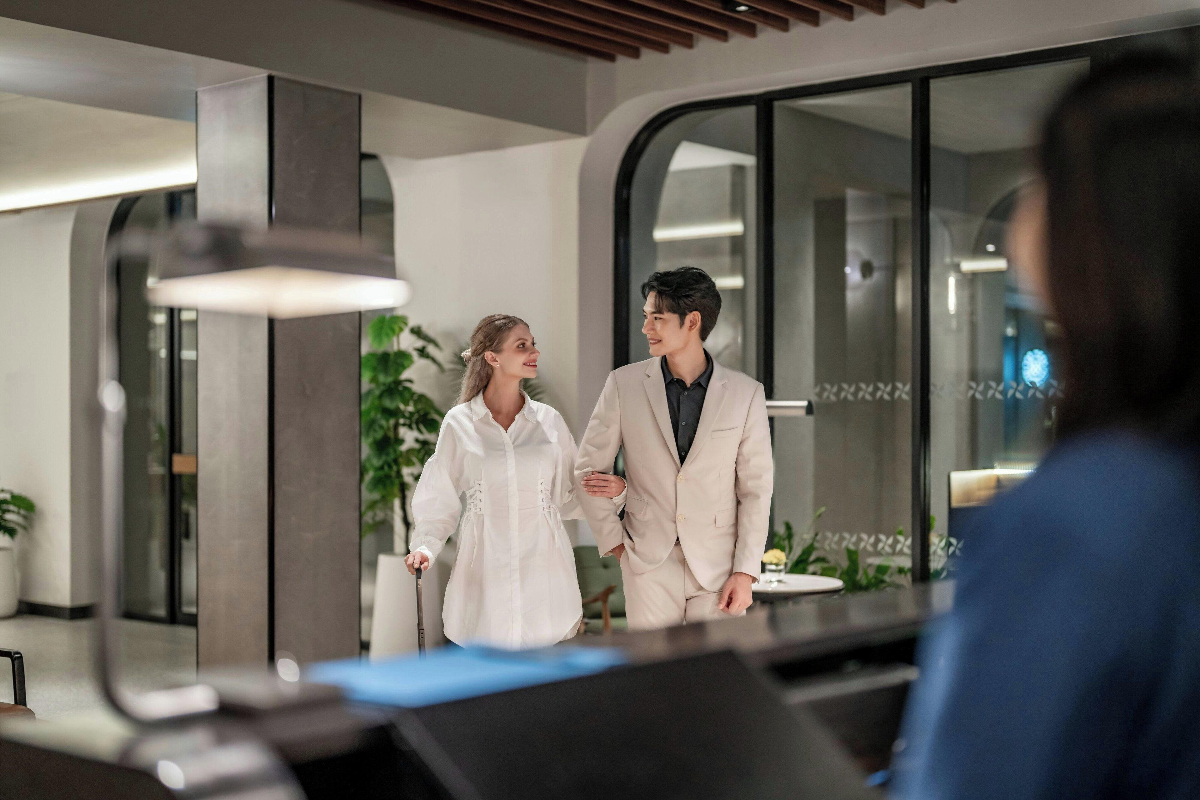 Un moderno vestíbulo de hotel con mostrador de recepción, un espejo grande y una planta en maceta.