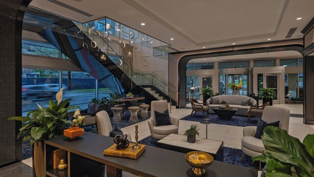 Un lobby moderno con una escalera, una zona de estar y amplias ventanas con vistas a la calle.