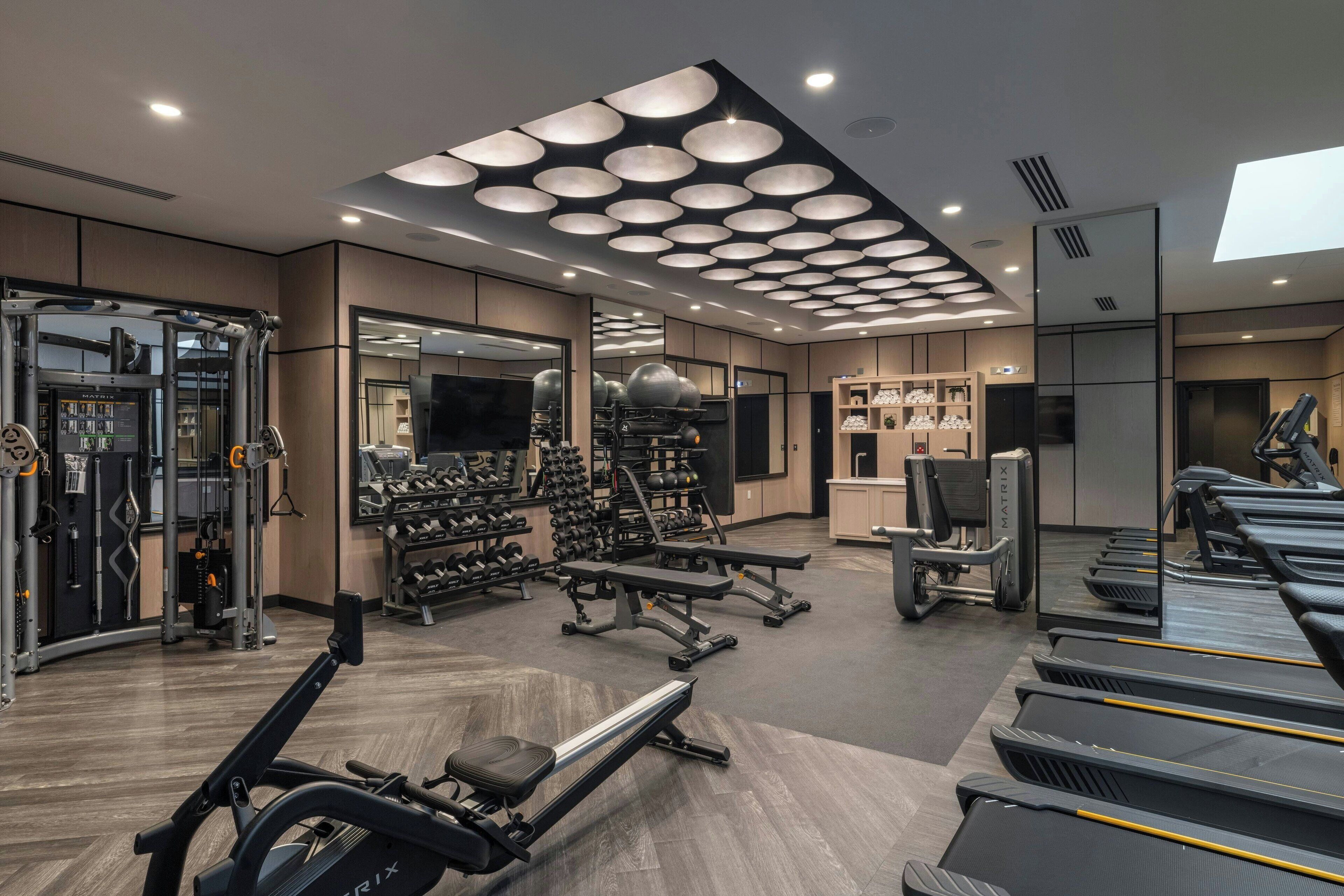 A modern gym with treadmills, weight machines, and free weights.