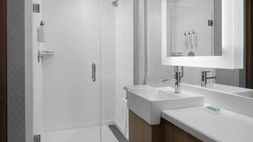 Un baño moderno con cabina de ducha de vidrio, dos lavamanos y un espejo grande.