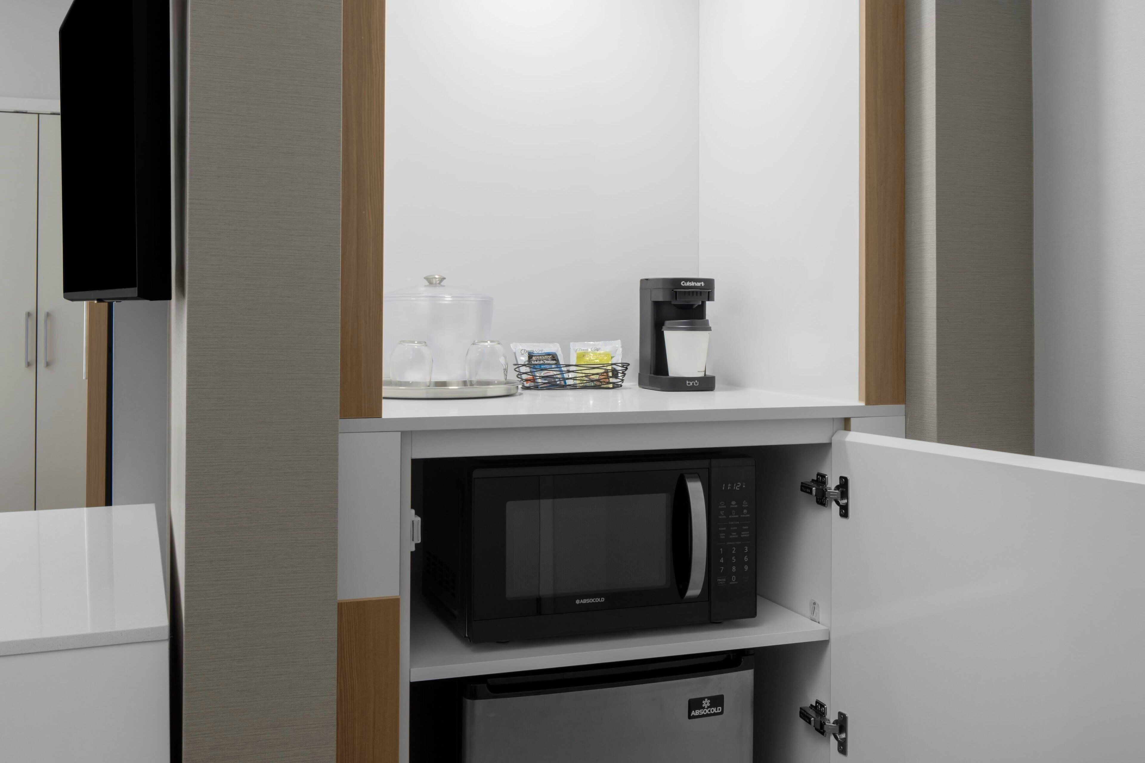A kitchenette with a microwave, coffee maker, and glass carafe.