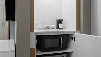 A kitchenette with a microwave, coffee maker, and glass carafe.