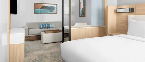 Una habitación de hotel moderna con cama, sofá, una mesita y un espejo.