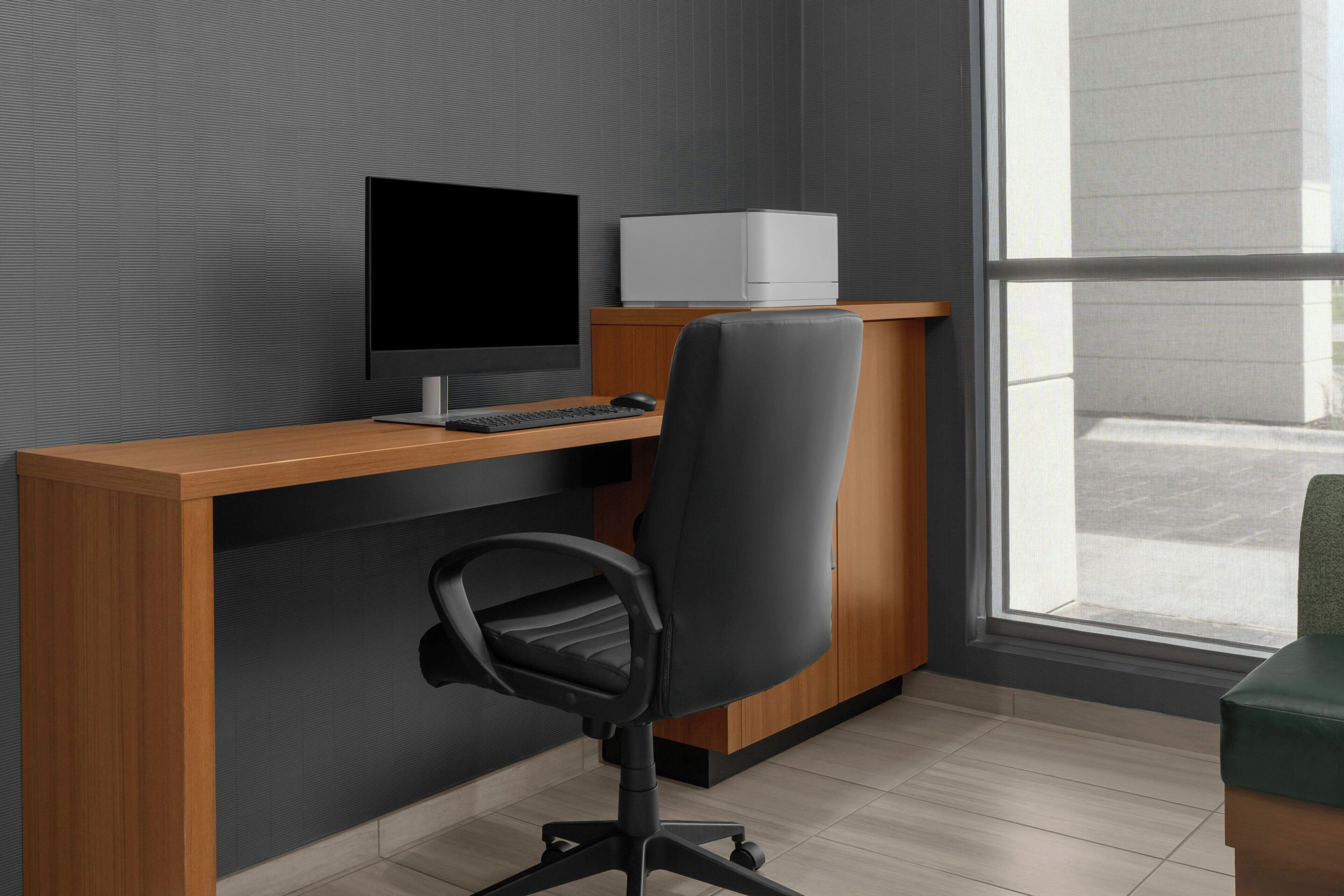 Un escritorio moderno con una computadora, una silla e impresora.
