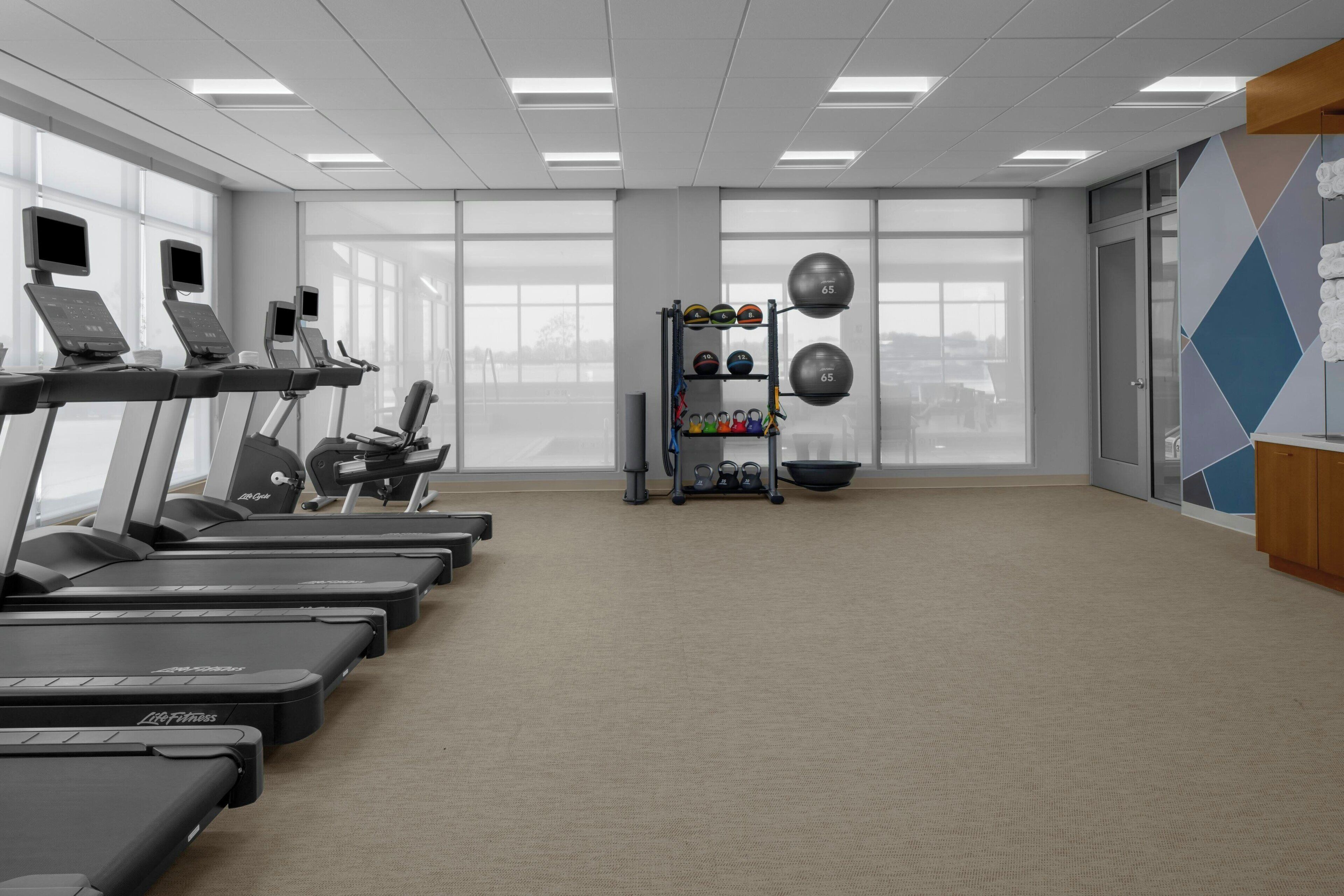 A gym with treadmills, weight machines, and a wall of exercise balls.