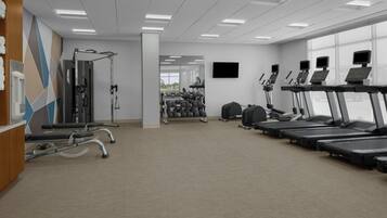 Une salle de sport équipée de tapis de course, d’appareils de musculation et d’haltères.