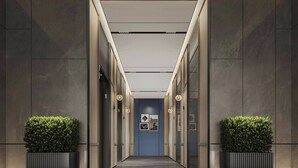 Un pasillo moderno con paredes oscuras, una pared azul de acento y dos plantas en macetas.