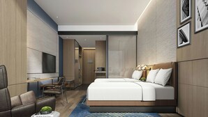 Una habitación de hotel moderna con una cama grande, un área de descanso con televisor y una pequeña mesa con un adorno.