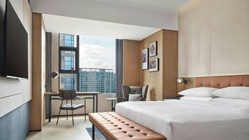 Una habitación de hotel moderna con una cama grande, un escritorio, una silla y vistas a la ciudad.
