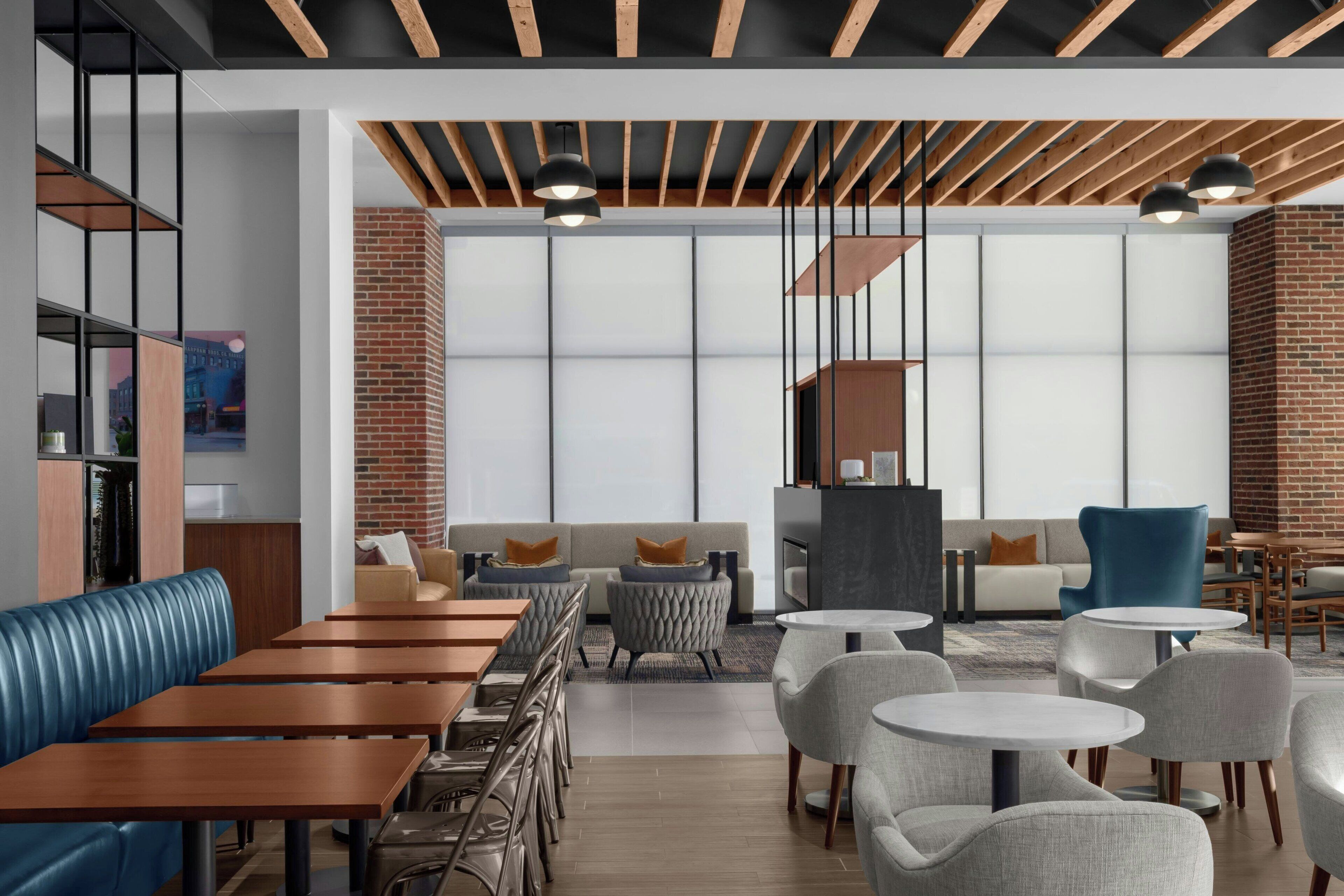 A modern interior with wooden beams, a brick wall, and a seating area with tables and chairs.