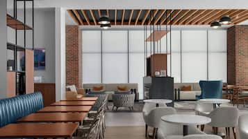 A modern interior with wooden beams, a brick wall, and a seating area with tables and chairs.