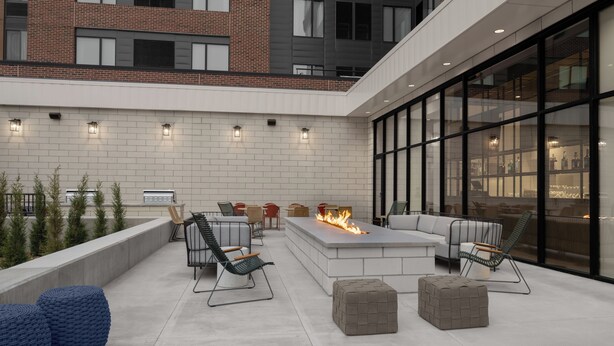 Un patio exterior con mobiliario, una chimenea y vistas de la ciudad.