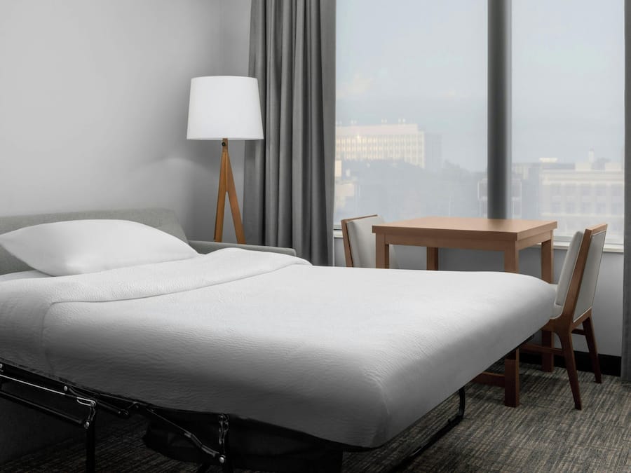 A hotel room with a bed, a table, and a chair.