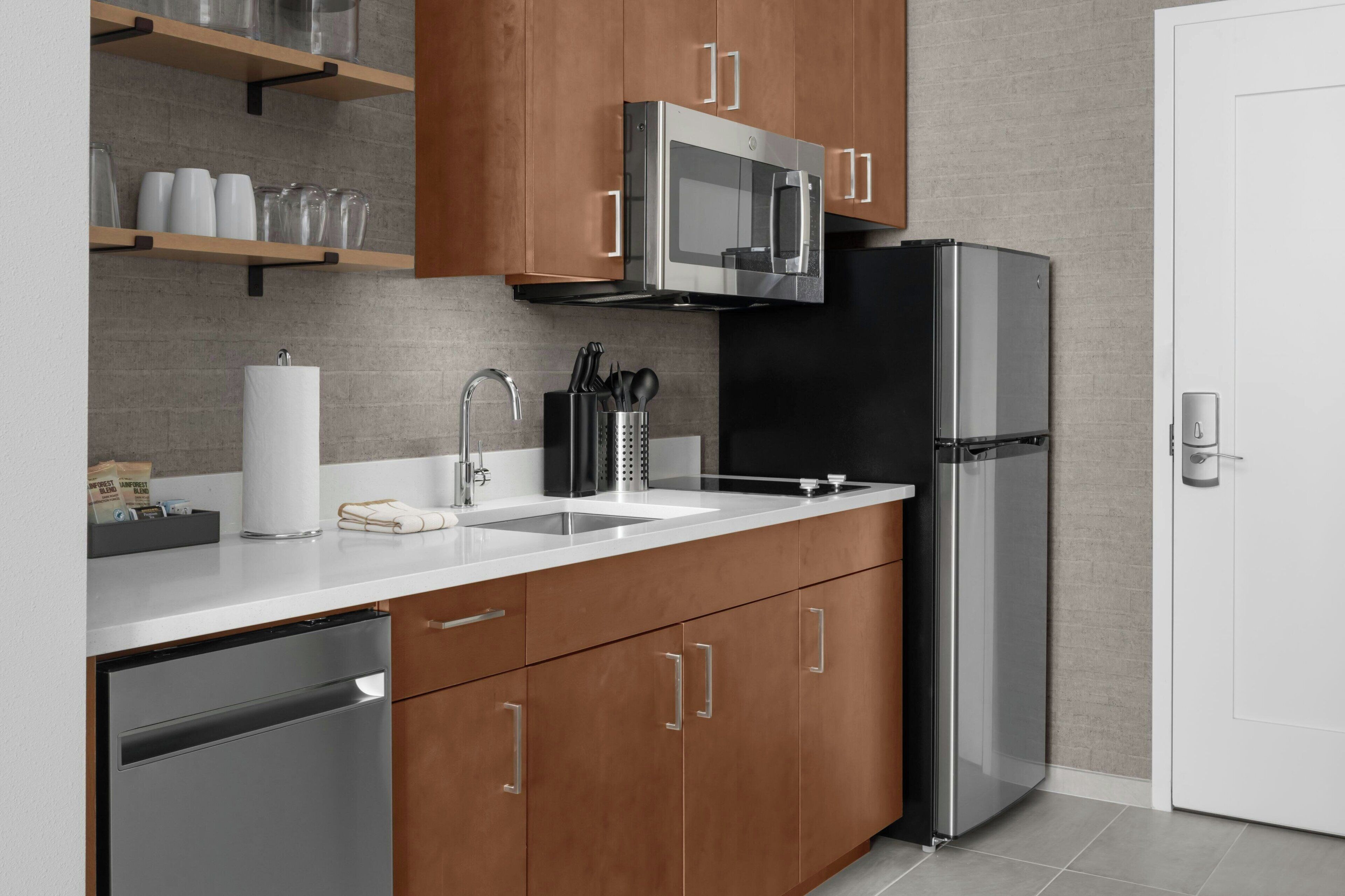 A modern kitchen with stainless steel appliances, wooden cabinets, and a white countertop.