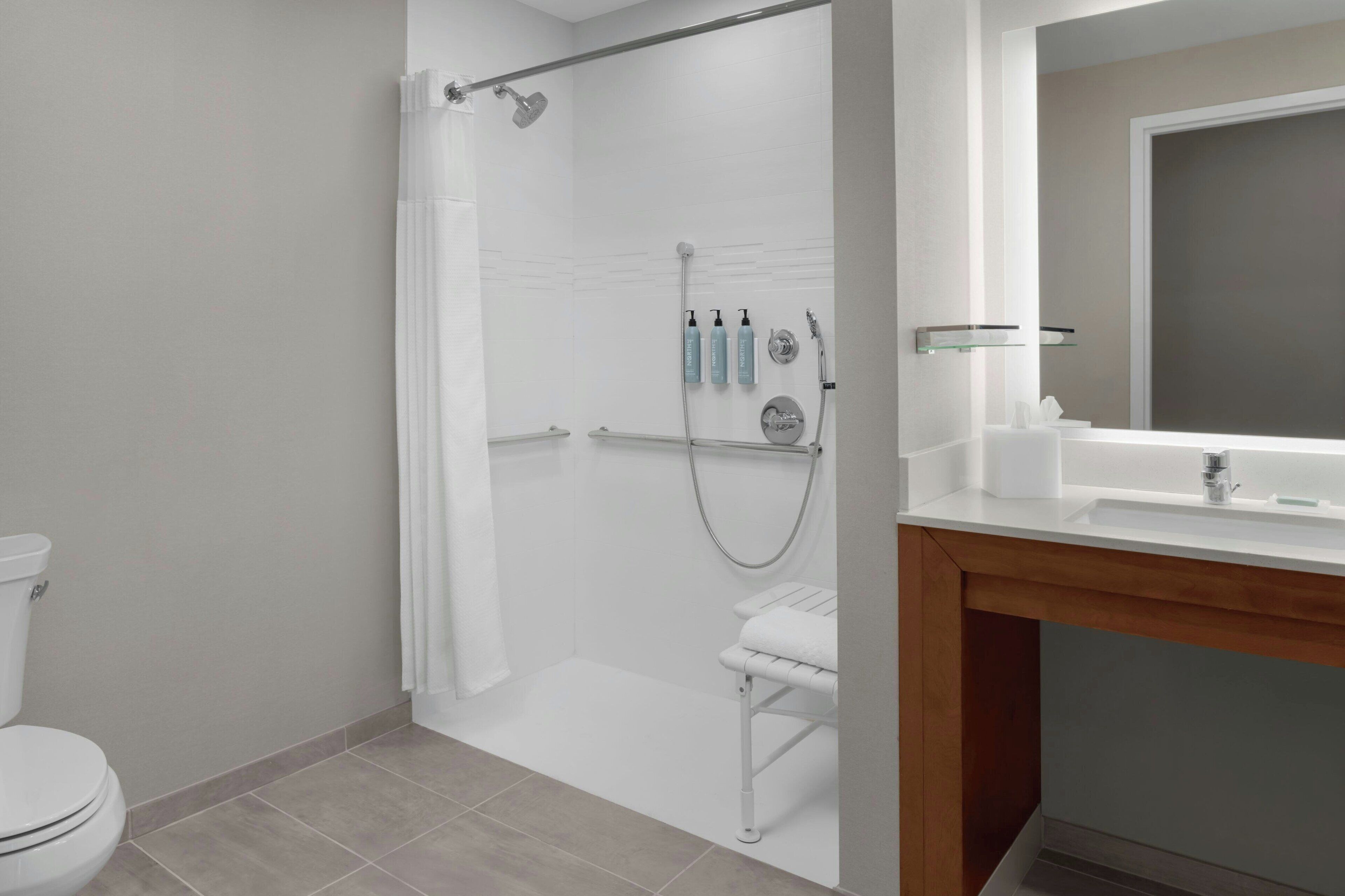 A modern bathroom with a shower, toilet, and sink.