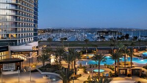 Un hotel con zona de piscina, puerto deportivo y vistas al puerto deportivo al atardecer.