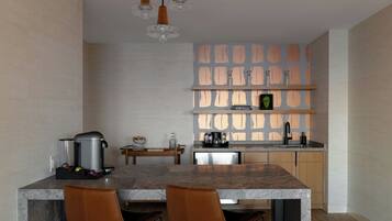 A modern kitchen with a marble countertop, two brown leather chairs, a coffee machine, and a coffee pot.