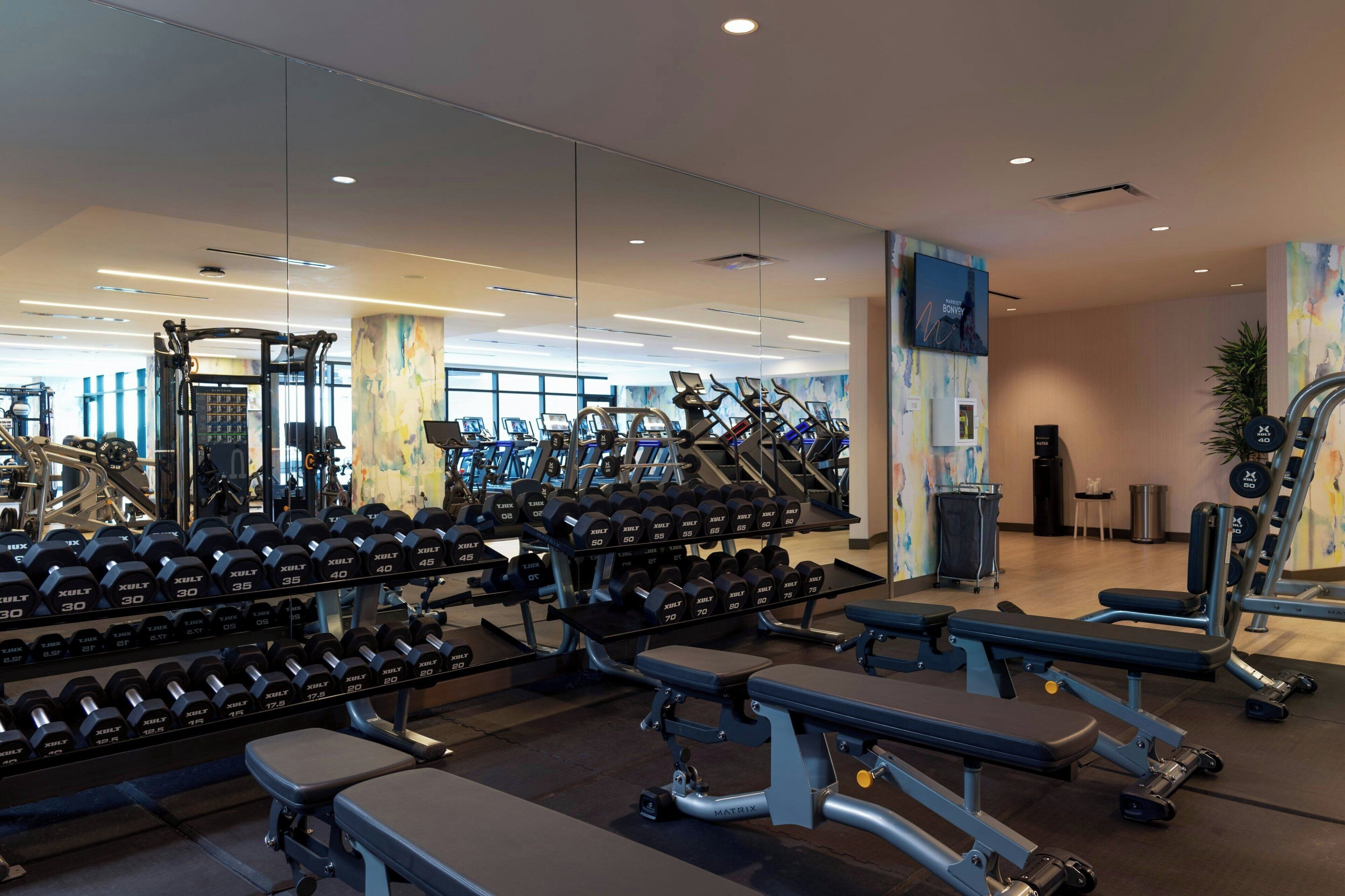 A modern gym with various exercise equipment, including dumbbells, treadmills, and weight benches.