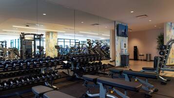 A modern gym with various exercise equipment, including dumbbells, treadmills, and weight benches.