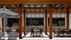 Un patio al aire libre con pérgola de madera, mesas, sillas y una barra con estantes llenos de botellas.