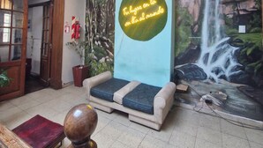 A lobby with a mural of a waterfall, a bench, a wooden table, and a potted plant. - Hostel Why not nva (Córdoba)
