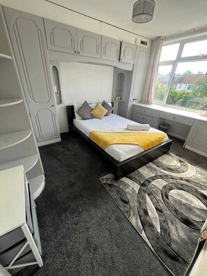 Une chambre à coucher avec un lit, un bureau, une chaise et une fenêtre donnant sur un beau paysage.