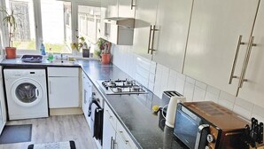 A modern kitchen with white cabinets, a built-in washing machine, a gas stove, and a microwave.