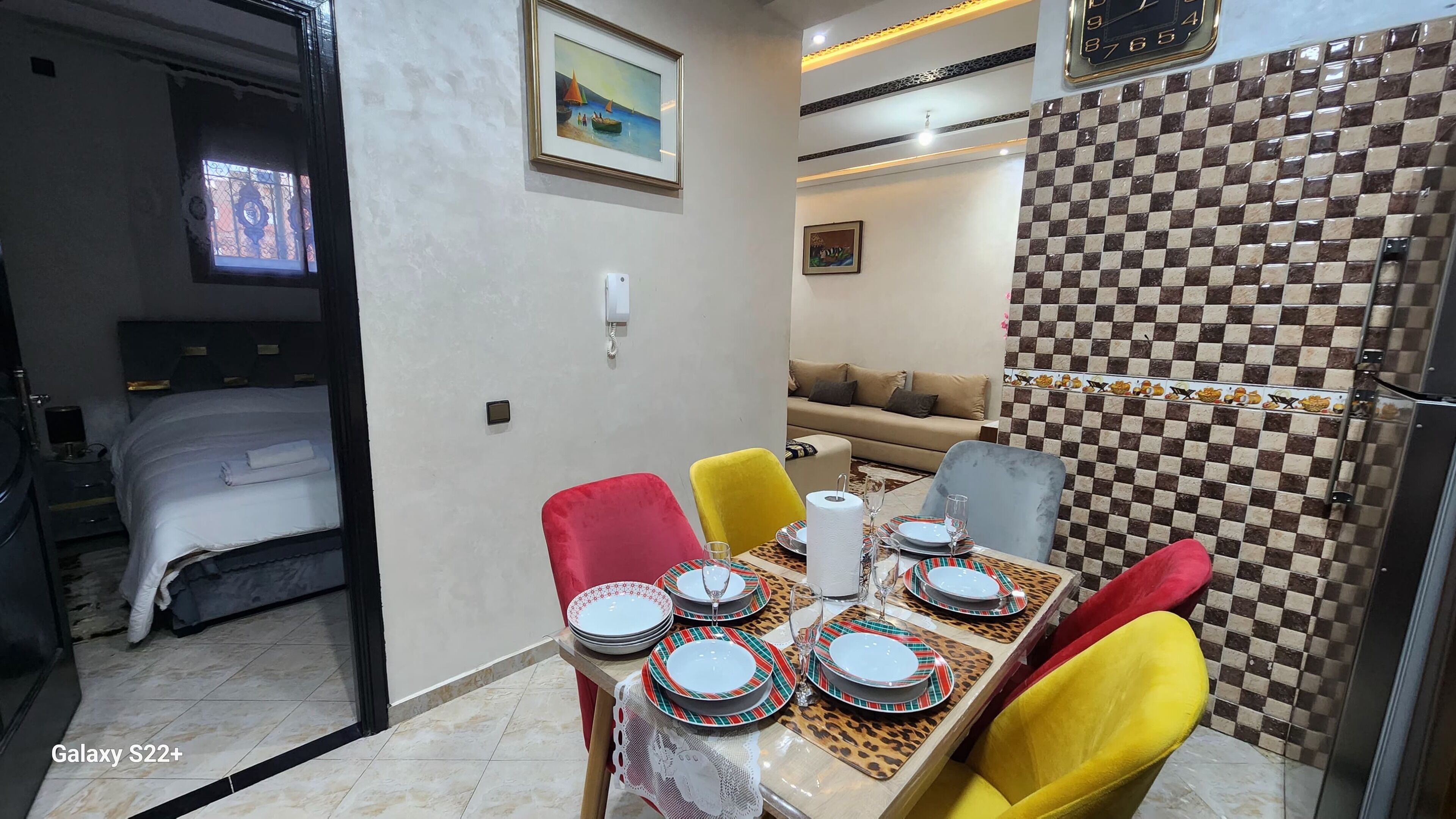 A hotel room with a dining area, a sofa, and a checkered wall.
