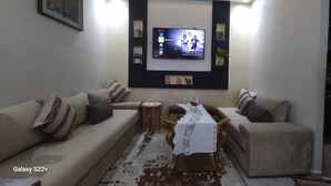 Una sala de estar con dos sofás, una mesa de centro y un televisor montado en la pared.