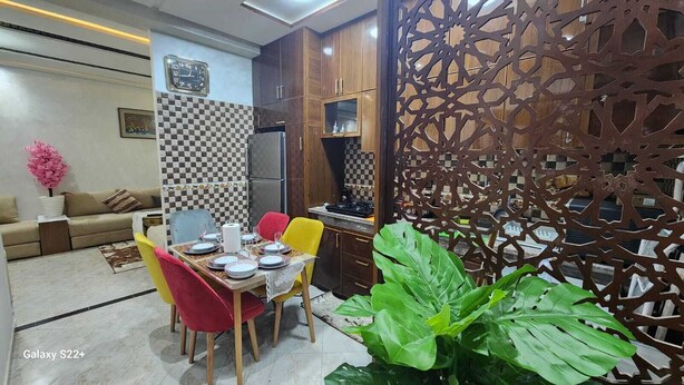 Un comedor con una pared a cuadros, un reloj y un separador decorativo.