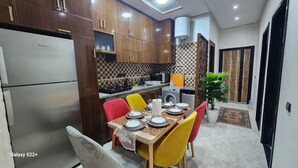 Una cocina moderna con armarios de madera, estufa integrada y una zona de comedor con mesa para cuatro.