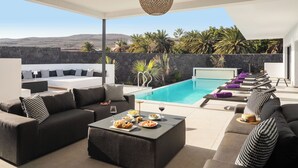 A modern outdoor living area with a pool, sofas, and a dining table set with food and drinks. - ODIN 2 by Buenavilla | Experience Unmatched Luxury in Puerto Calero (Puerto Calero)
