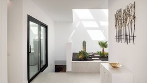 A modern interior with a glass door leading to a balcony, a minimalist white console table, and a wall-mounted decorative piece. - ODIN 2 by Buenavilla | Experience Unmatched Luxury in Puerto Calero (Puerto Calero)
