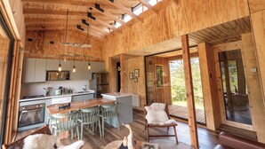 Un interior moderno de madera con cocina, comedor y ventanas amplias.