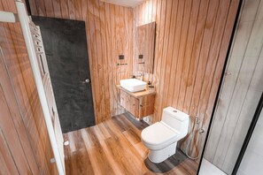 A bathroom with wooden panel walls, a white sink, and a toilet.